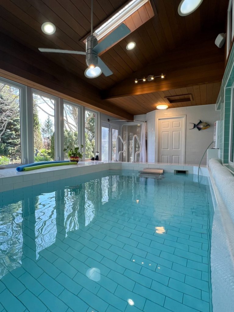 Heated luxury indoor pool with an endless swim machine, stained cedar ceilings, and large windows looking out to the gardens at Wind in the 